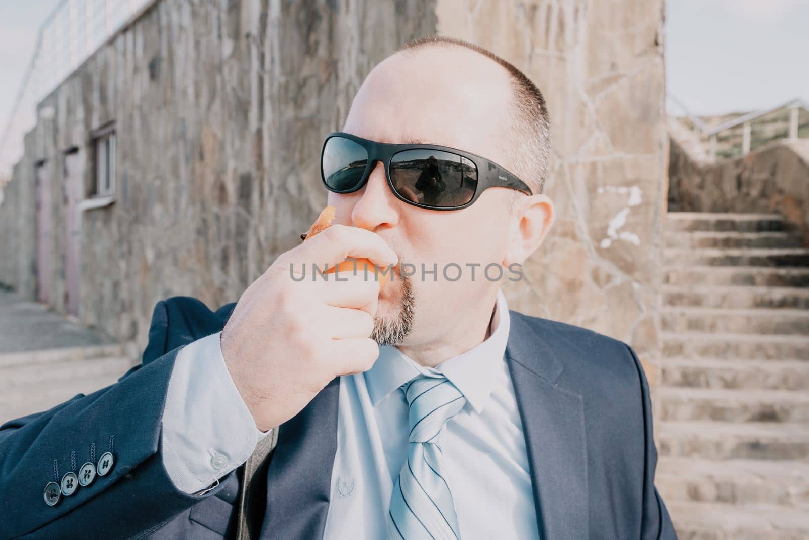 Male persimmon park. Hipster millennial man in a tie and jacket bites off a persimmon while sitting on a park bench in slow motion Young business people eat golden persimmons at lunchtime