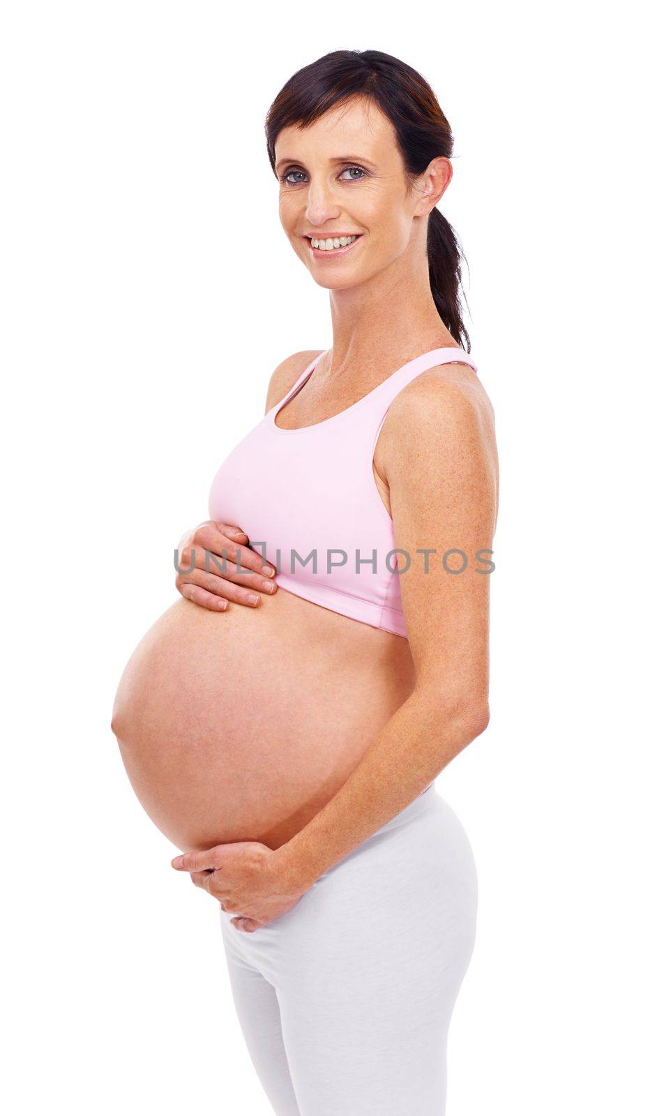 I cant wait to meet my little one. A proud pregnant mother holding her stomach while smiling at the camera