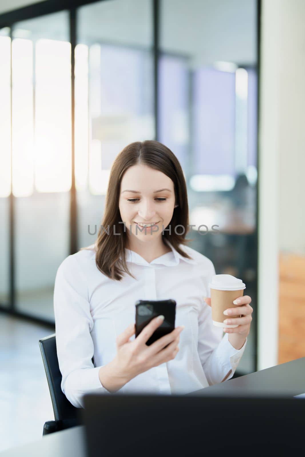 Portrait of a business woman talking on the phone and drinking coffee.