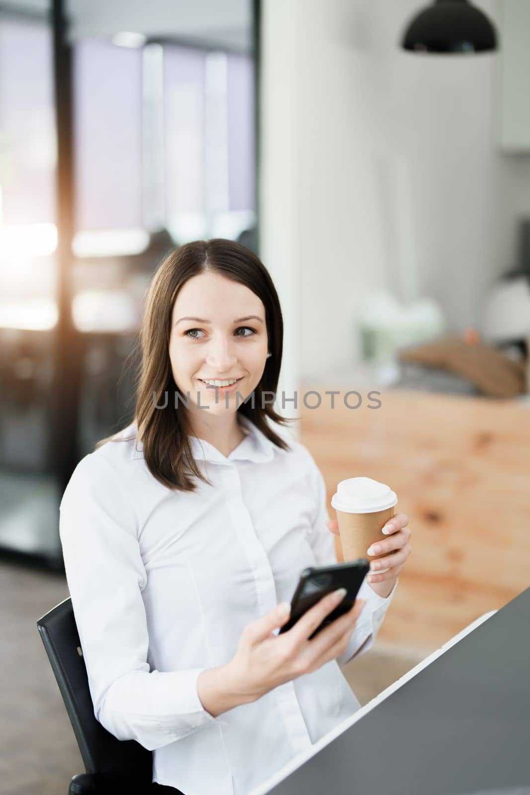 Portrait of a business woman talking on the phone and drinking coffee.