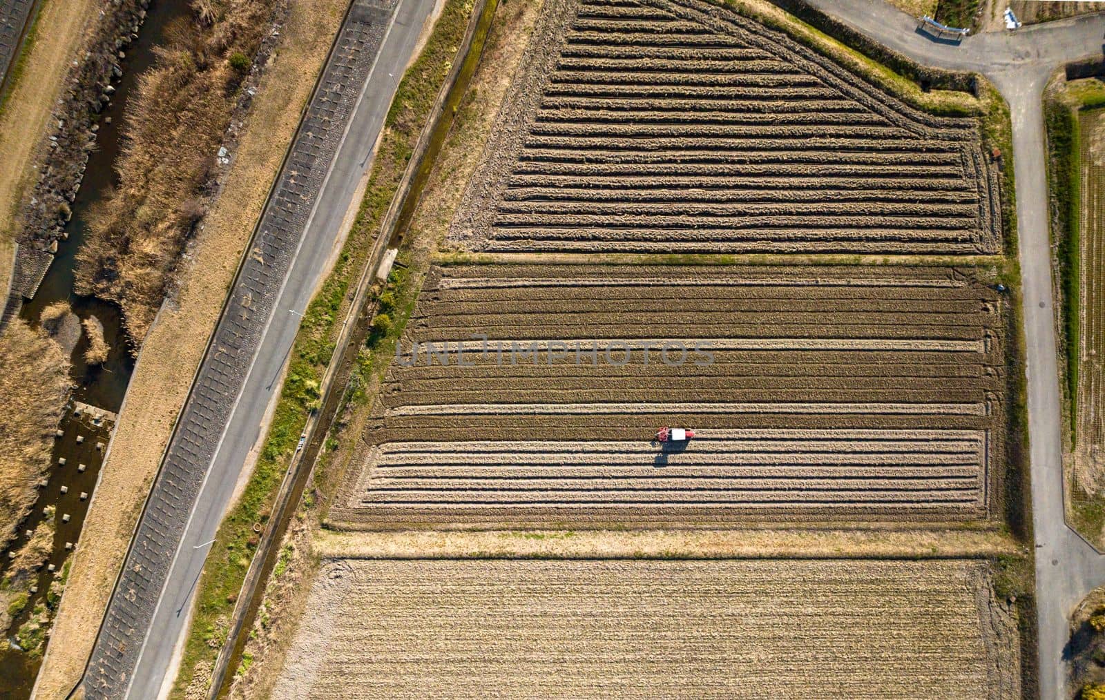 Aerial Overhead View of Tractor Plowing Fallow Field in Rural Agriculture Landscape by Osaze