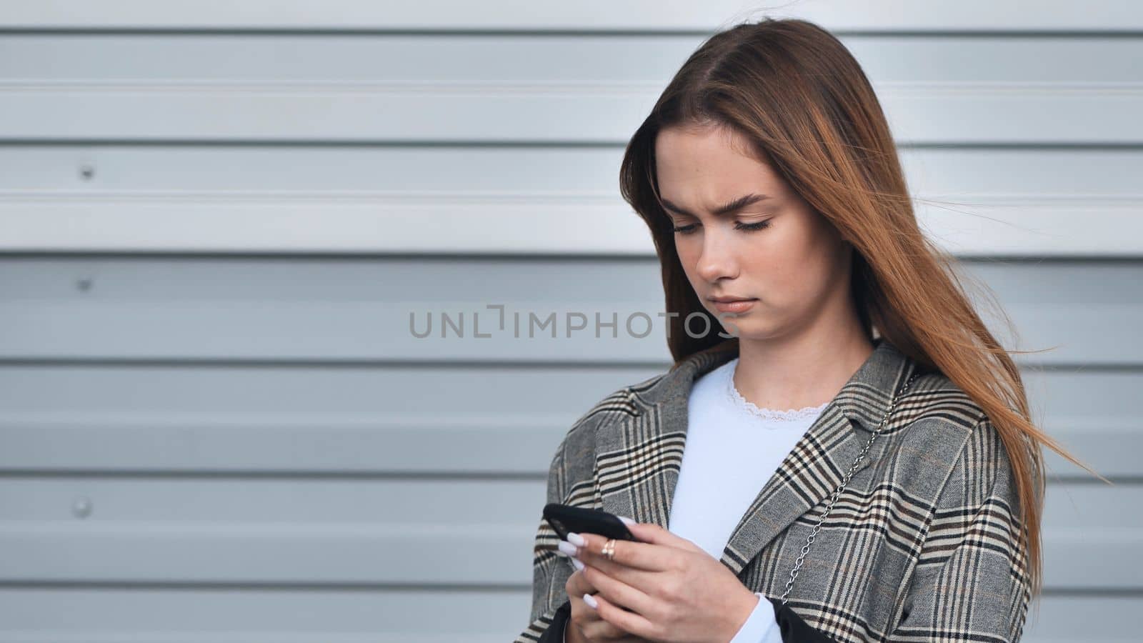 A girl looks into a smartwatch against a striped wall