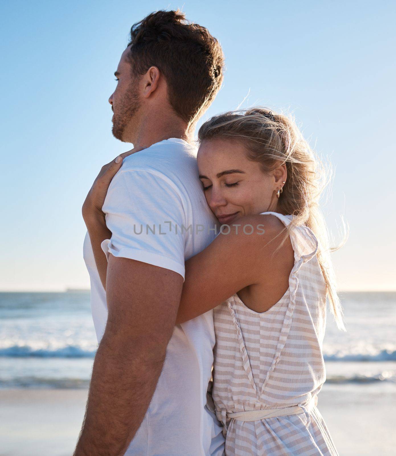 Hug, love and beach with a young couple enjoying a date in nature together for romance or vacation. Summer, travel and hugging with a man and woman dating on a coast holiday by the sea or ocean by YuriArcurs