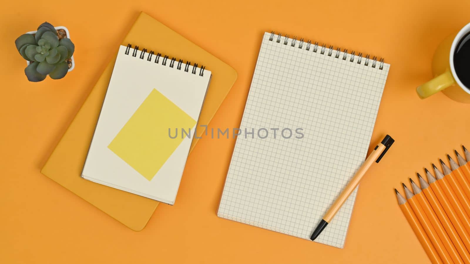Top view of blank notepads, sticky note, pencils and coffee cup on yellow background by prathanchorruangsak