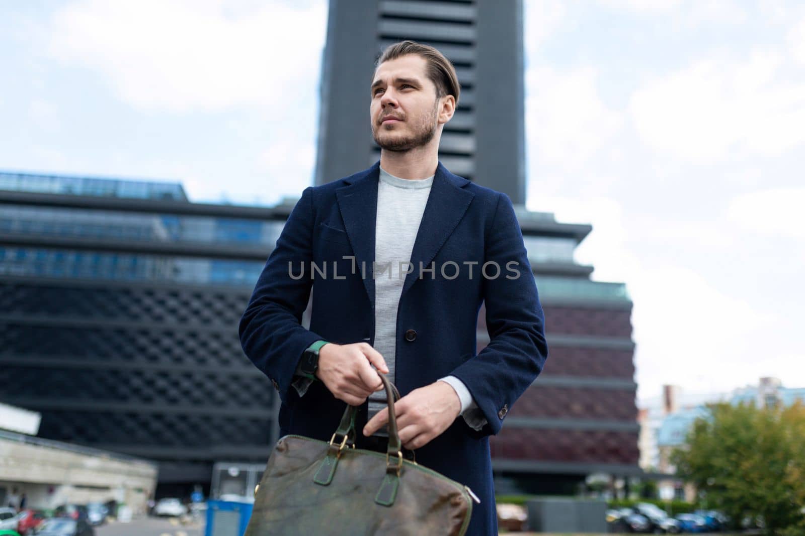 business man caucasian appearance with a bag for documents on the background of city administrative buildings.