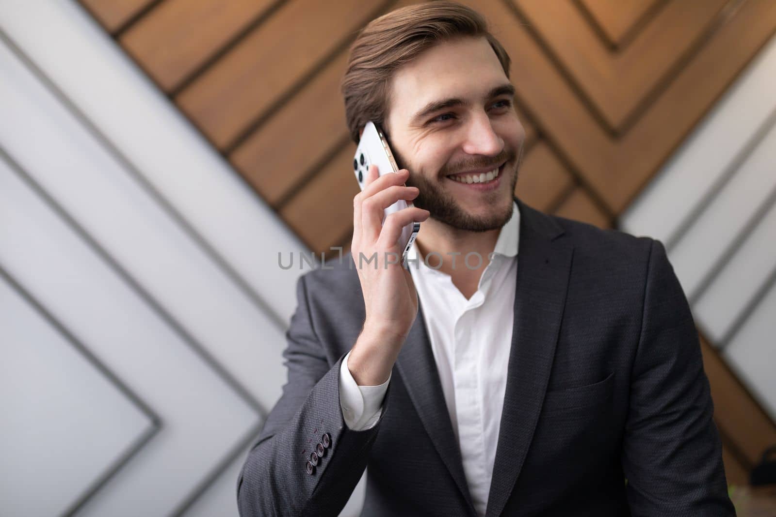 confident man businessman in a jacket speaks on the phone in the office.