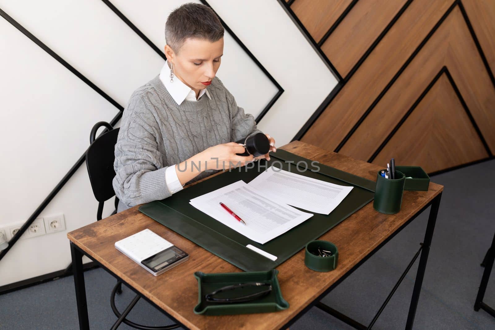 mature caucasian woman with short haircut is working in the office with documents.