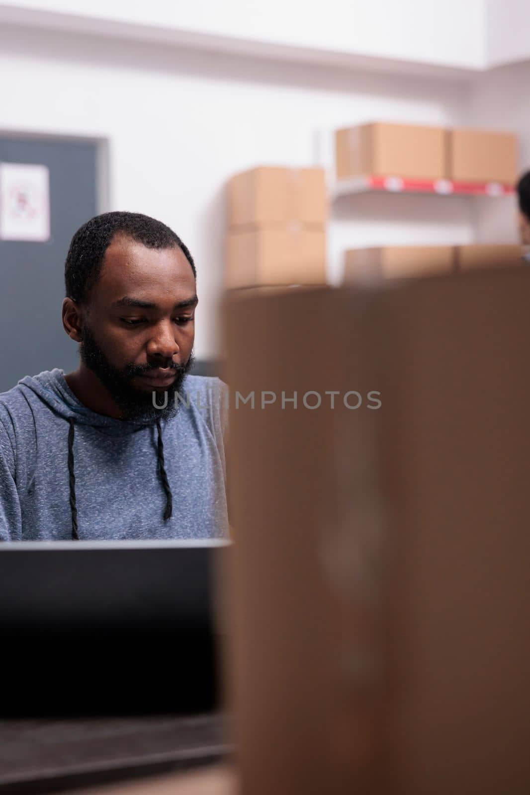 Storehouse manager checking shipment logistics before start preparing packages, putting customer order in carton boxes. African american supervisor working in warehouse delivery department