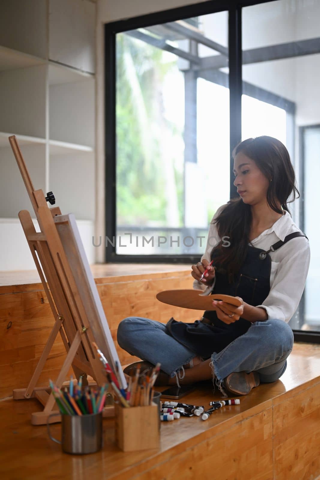Pretty female painter painting on easel in her studio.