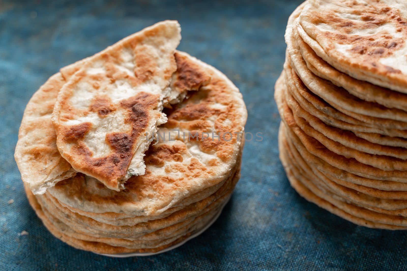 Flatbread lavash, chapati, naan, heap of tortilla on a blue background Homemade flatbread stacked