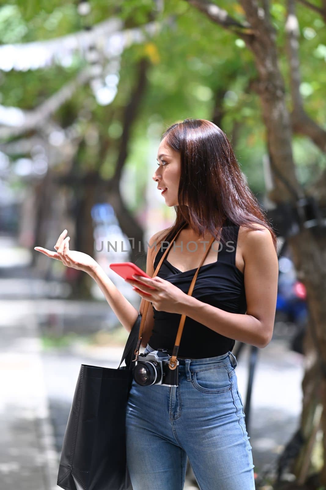 Female traveler holding smart phone and walking in the city street.