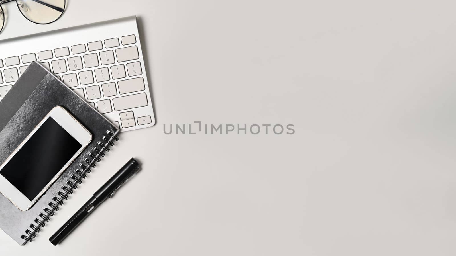 Top view mock up smart phone, notebook and glasses on white table. by prathanchorruangsak