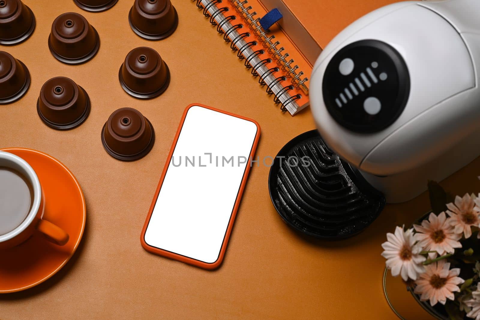 Mock up smart phone, coffee maker and capsules on brown leather. by prathanchorruangsak