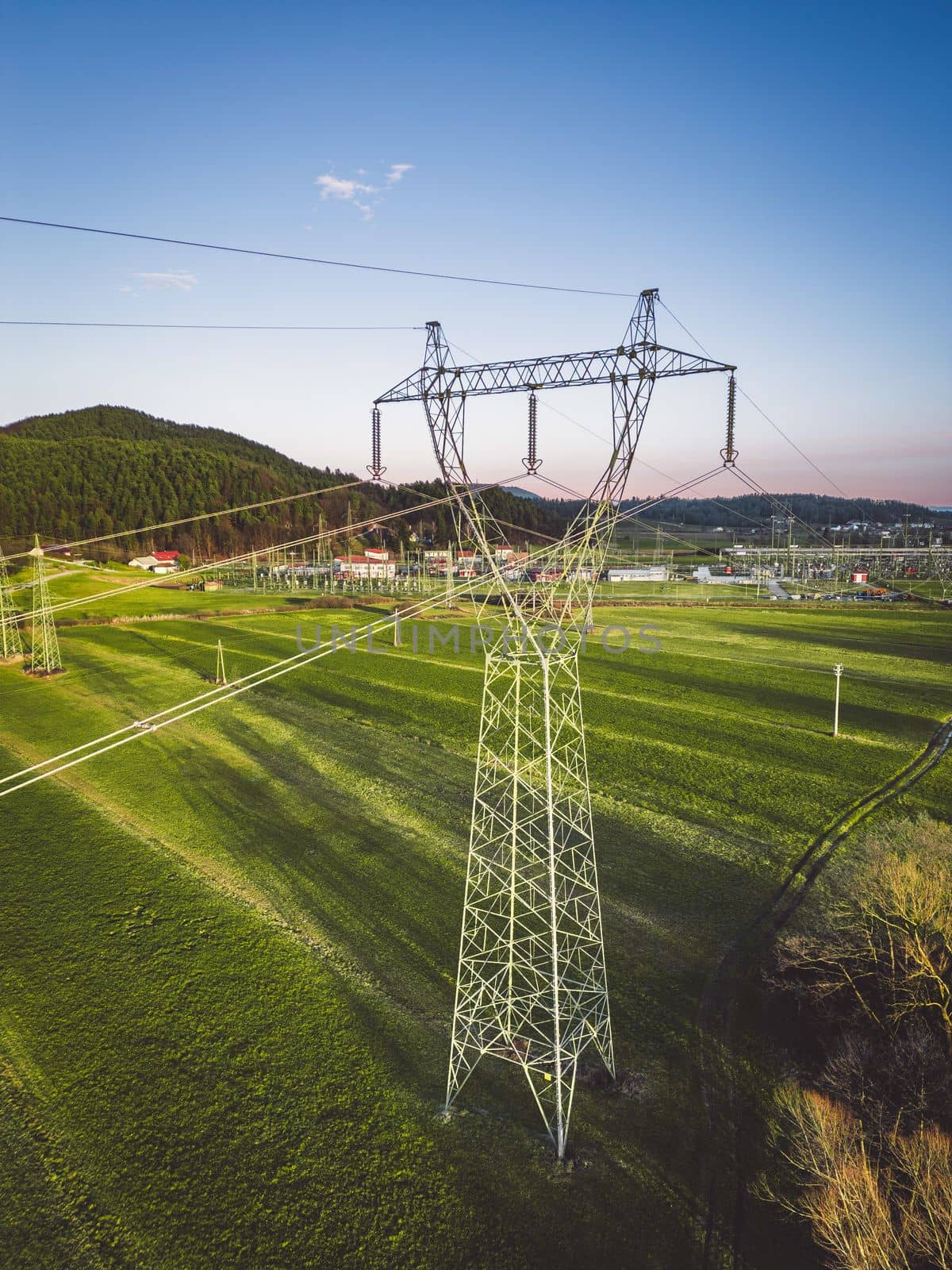 Vertical phot of electrical tower on a grass field in the country side of Slovenia by VisualProductions