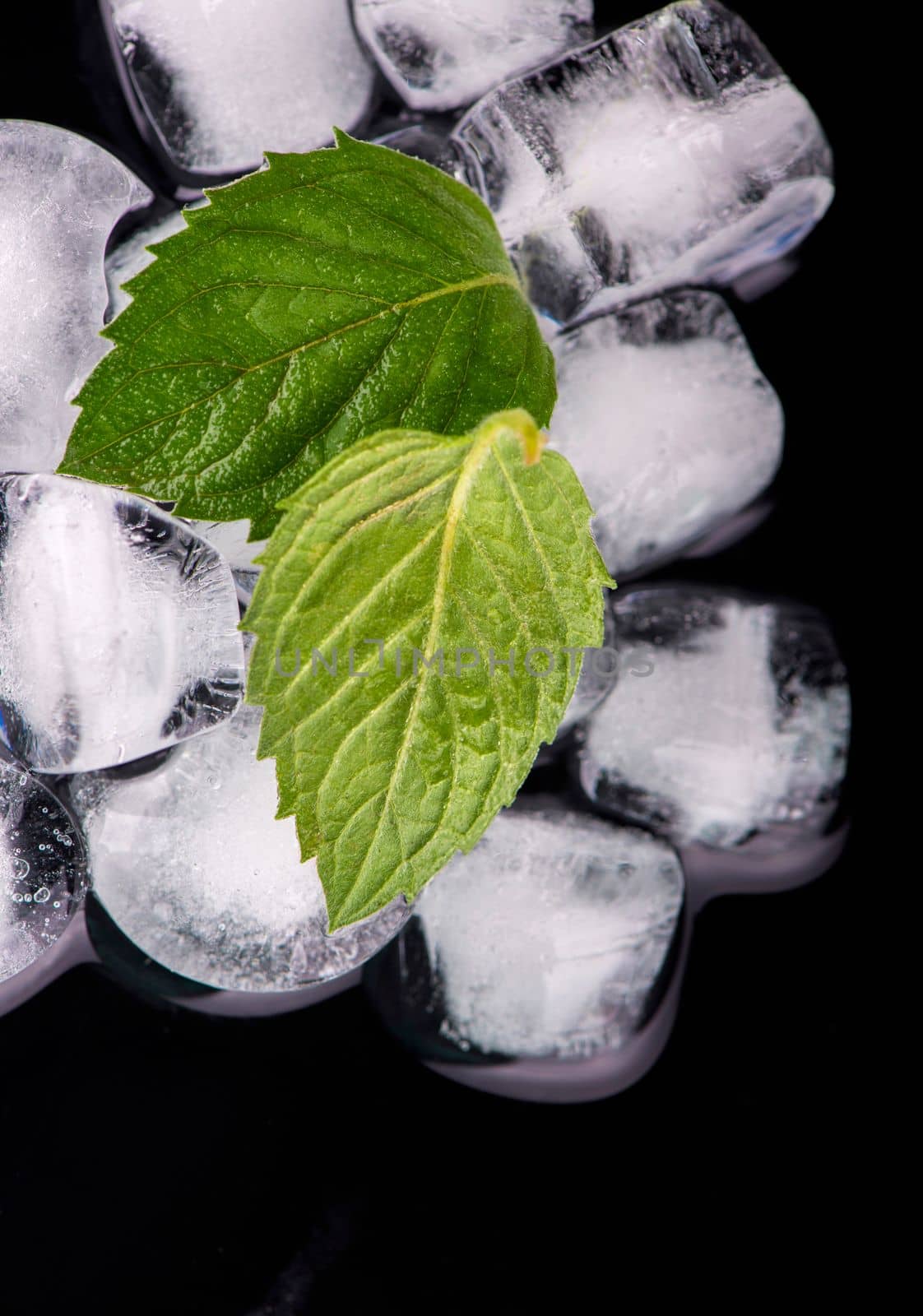 Cocktail preparation. Ice cube with mint leaves on black background by aprilphoto