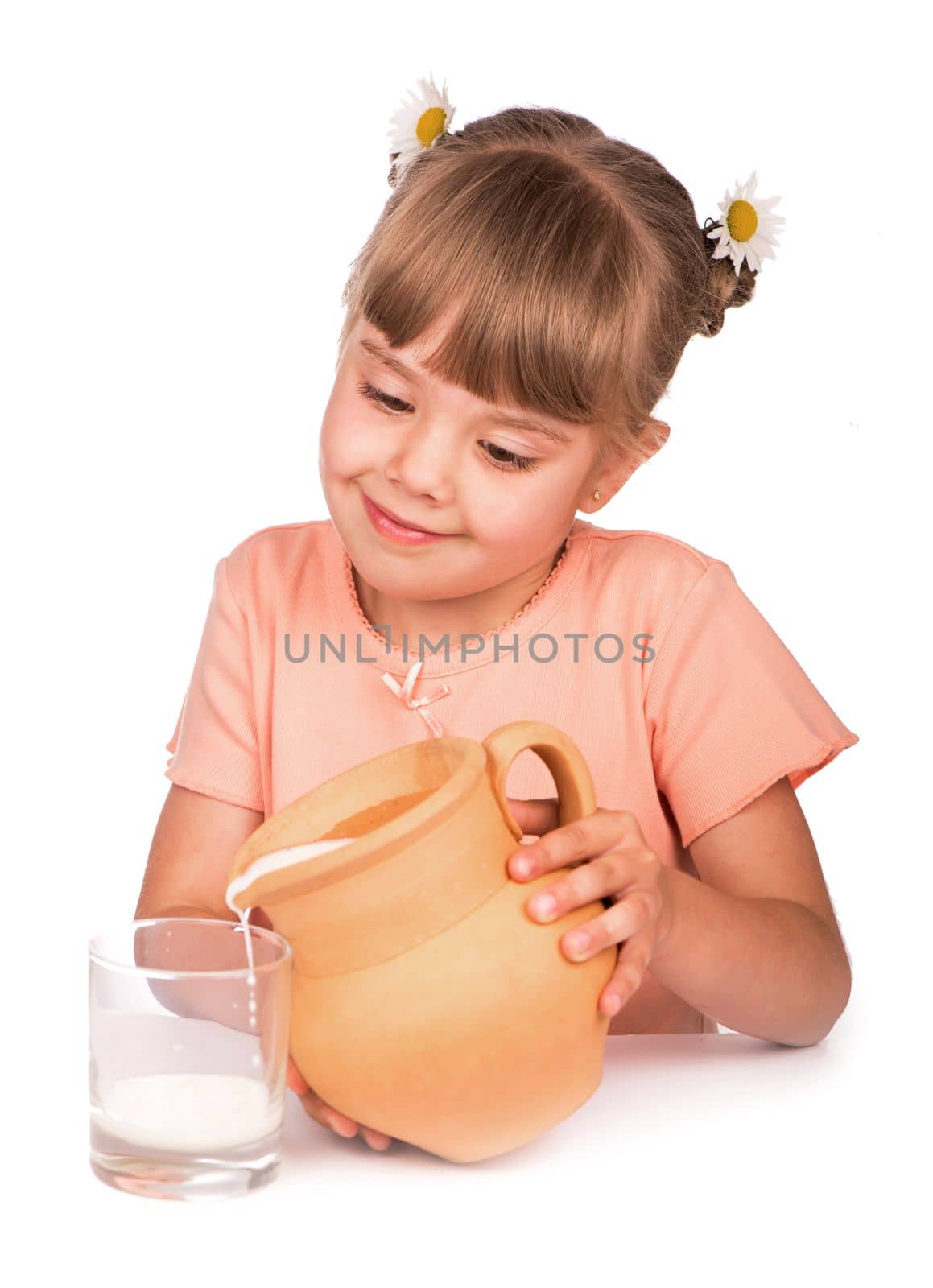 a girl in an orange T-shirt and flowers in her hair pours fresh milk from a jug on a white background by aprilphoto