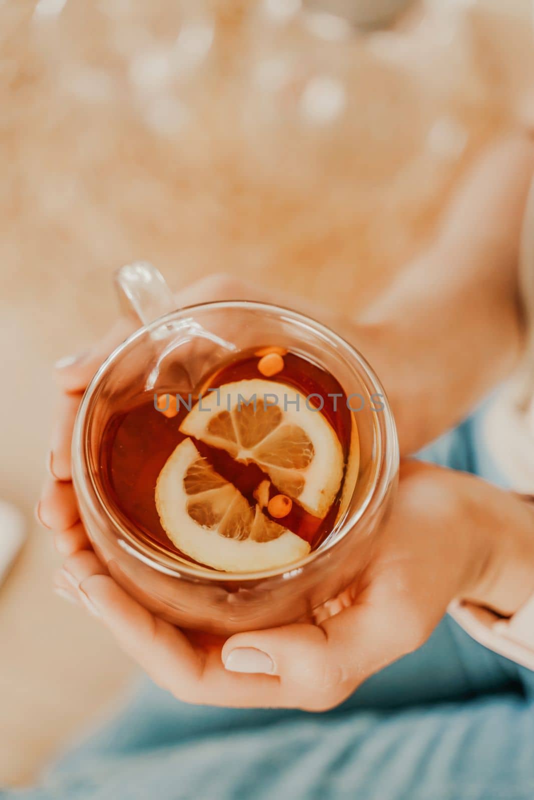 Cup of tea with lemon in female hands. Top view of female hands holding a transparent cup of tea with lemon. by Matiunina