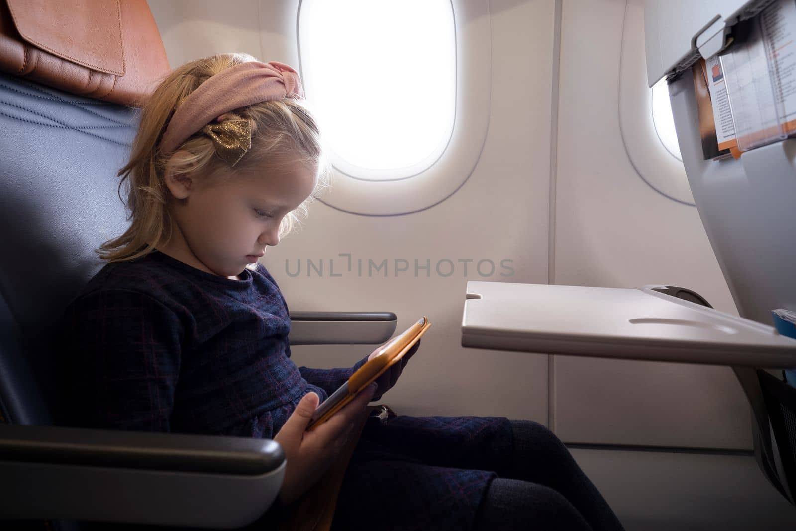 Little girl in airplane with tablet by gcm