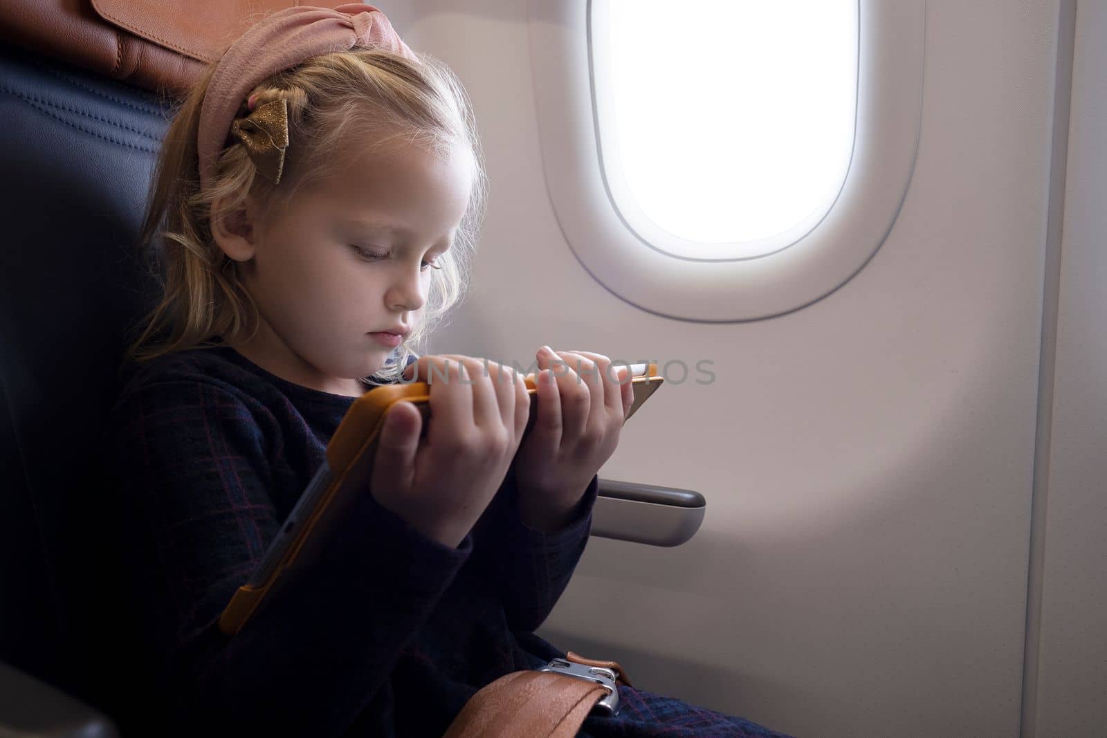 Focused girl watching video on tablet in plane by gcm