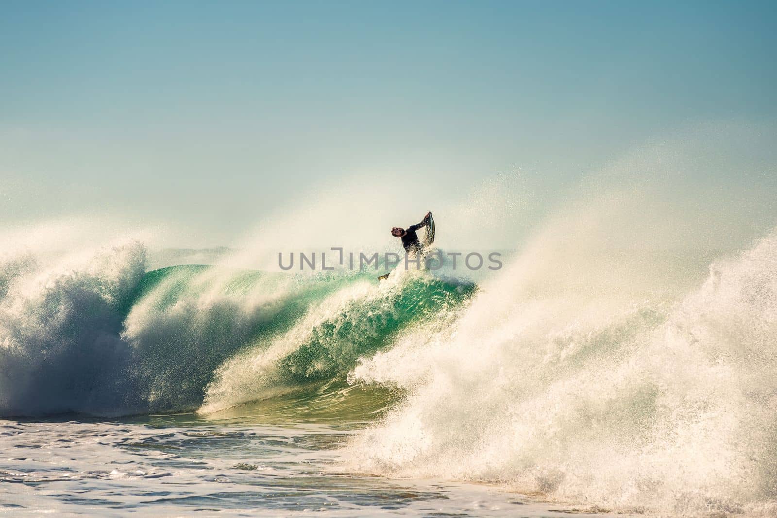 Surfer jumping a powerful and big wave at sunset by raulmelldo