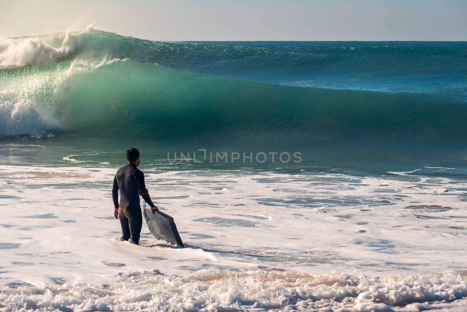 Surfer with board watches the waves from the shore by raulmelldo