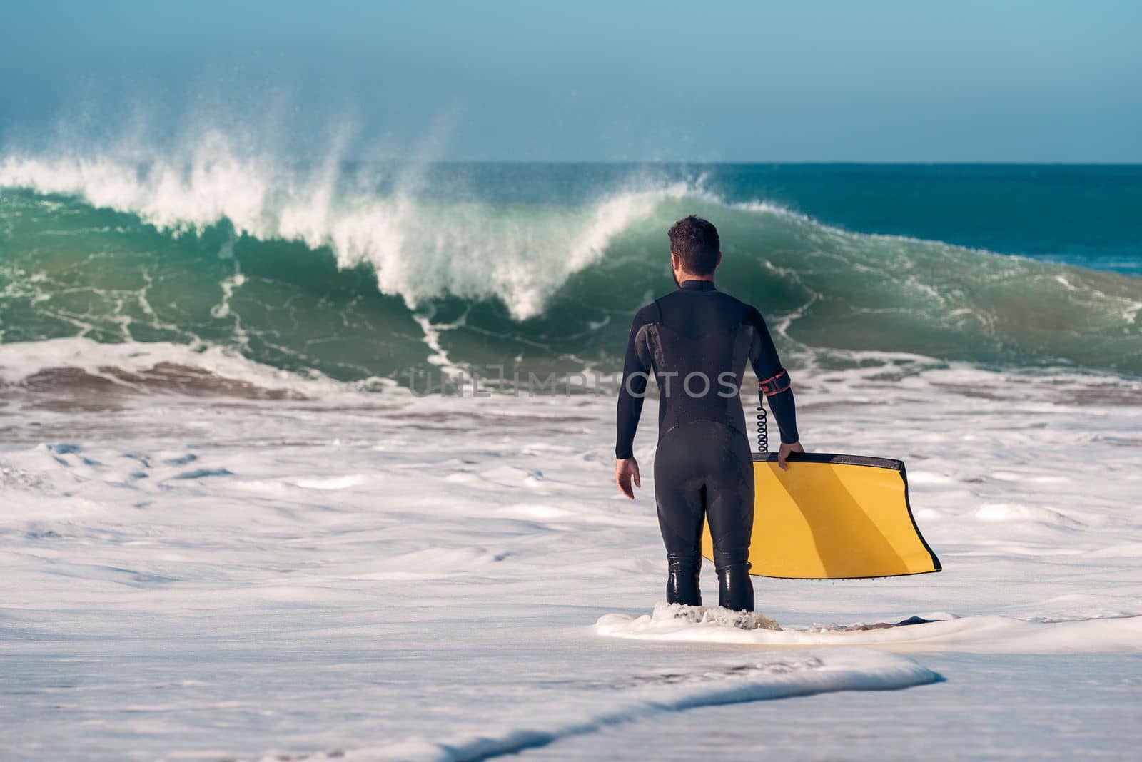 surfer with board watching big wave from the shore by raulmelldo