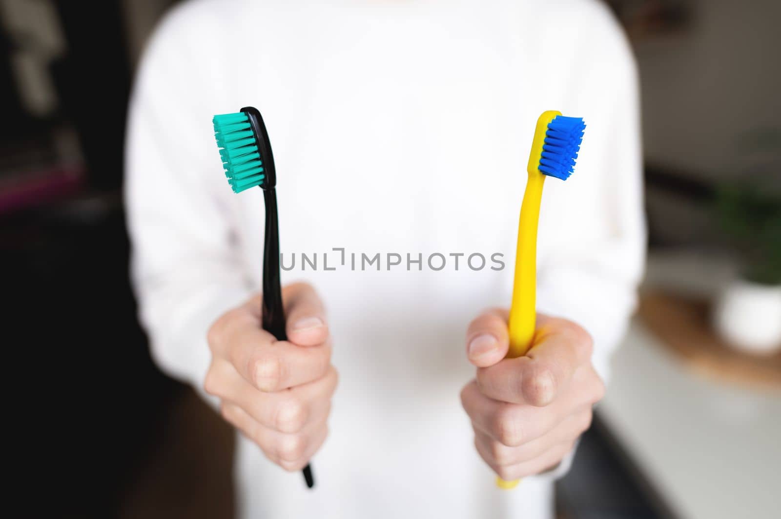 Woman's hand holds two toothbrushes. Dental direction, the subject of the morning hygiene of a married couple.