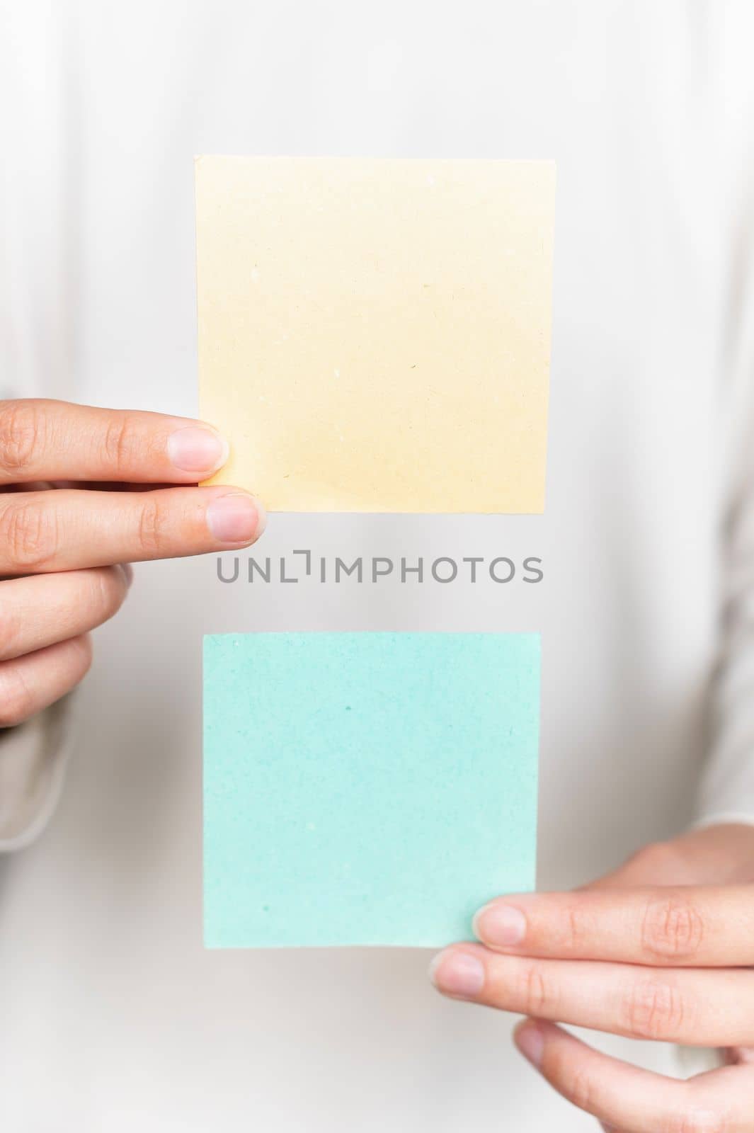 Female hands hold blank brochure booklets on a blurred white jacket background. Sheet template. Sticker reminder.