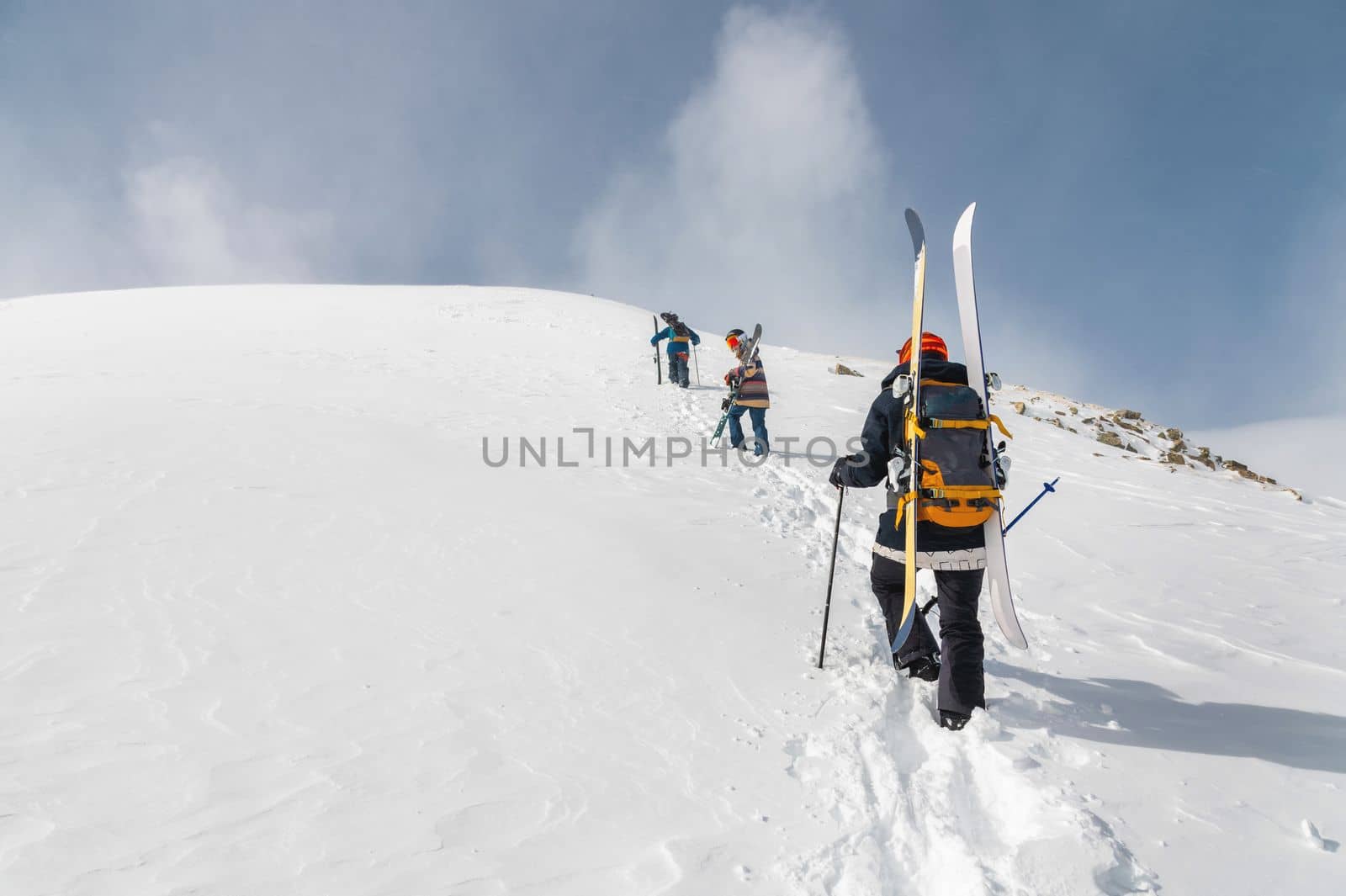 Backcountry climbers, ski climber, walking with skis and snowboard in the mountains. Ski tourism in the alpine landscape. Adventure winter sport.