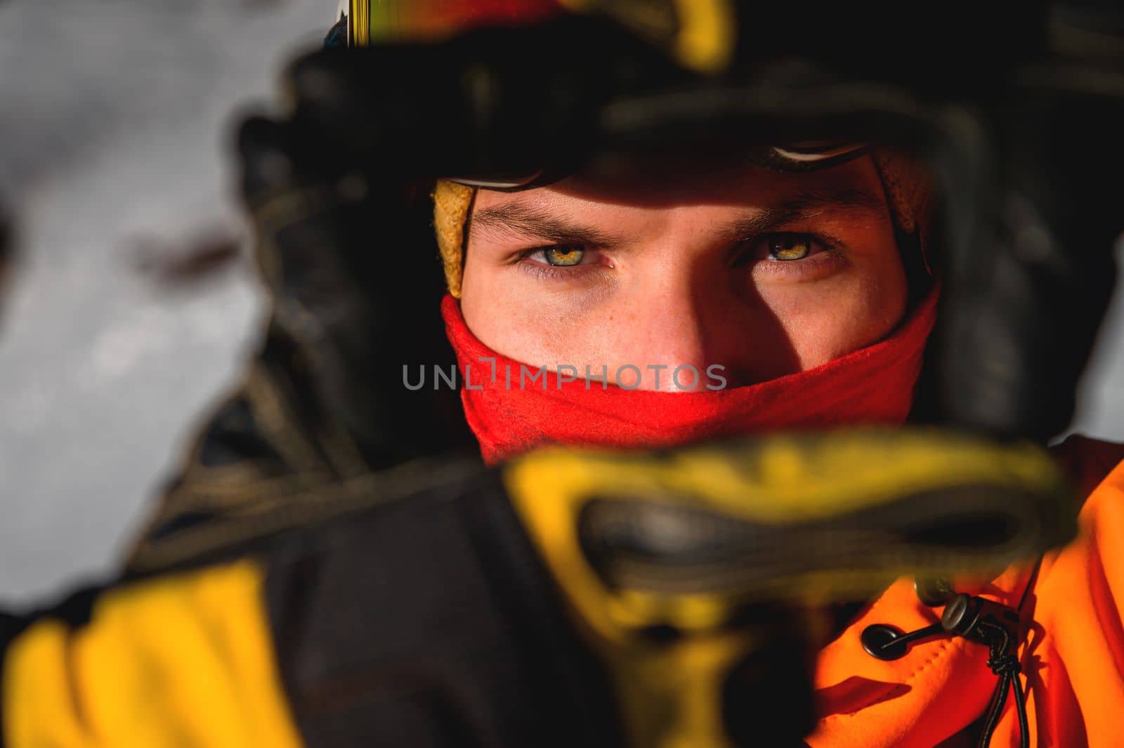 portrait of a man in a balaclava and a ski helmet on his head. Close-up of a caucasian man's face looking at the camera, bright eyes.