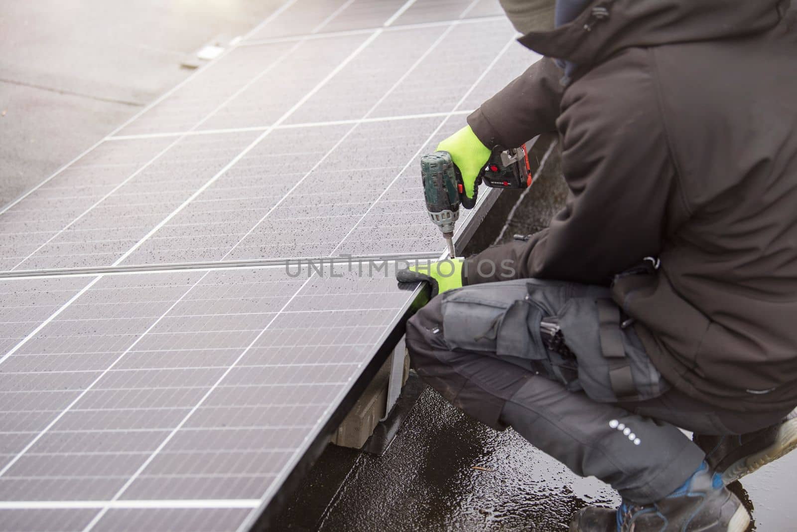 Renewable energy. Green energy concept. The process of installing solar panels. The master tightens the mounting of the solar panel module. by SERSOL