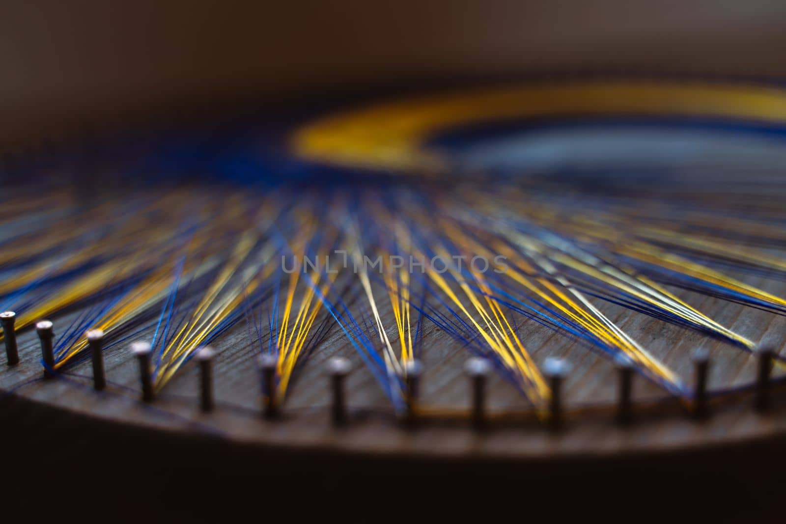 Colored thread mandala on a wooden board with nails. Mandala Moon Harmony Sun esotericism and psychology pictures from yellow and blue silk threads