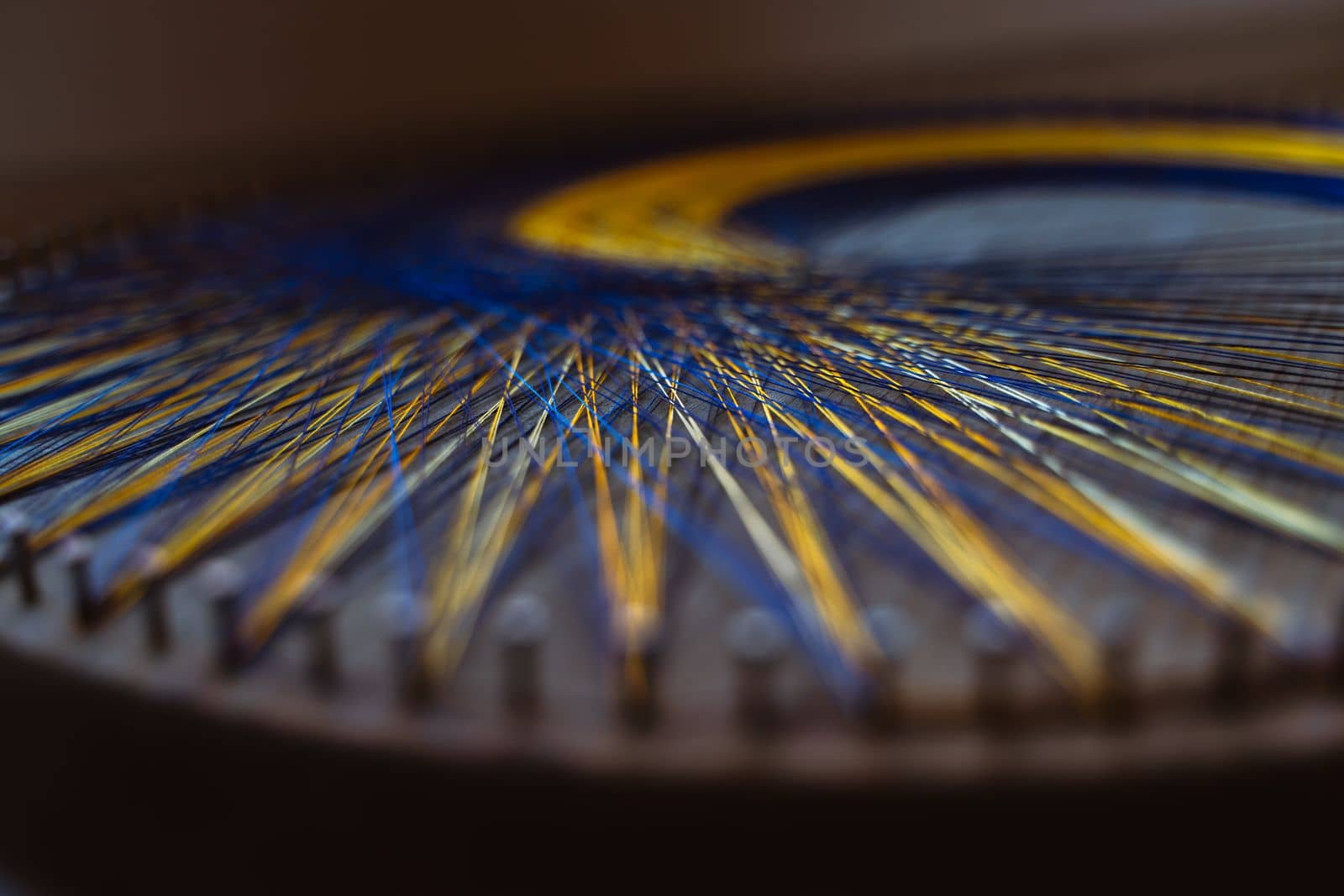 Colored thread mandala on a wooden board with nails. Mandala Moon Harmony Sun esotericism and psychology pictures from yellow and blue silk threads. by Matiunina