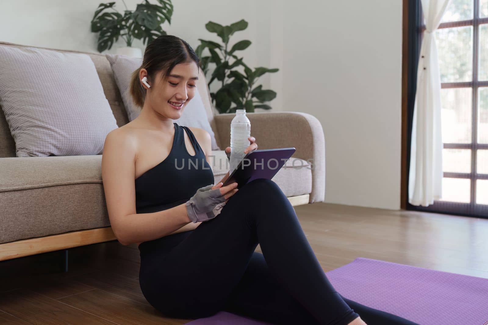 Healthy asian woman practicing relaxation yoga at home. Spending time and playing digital tablet at home concept by itchaznong