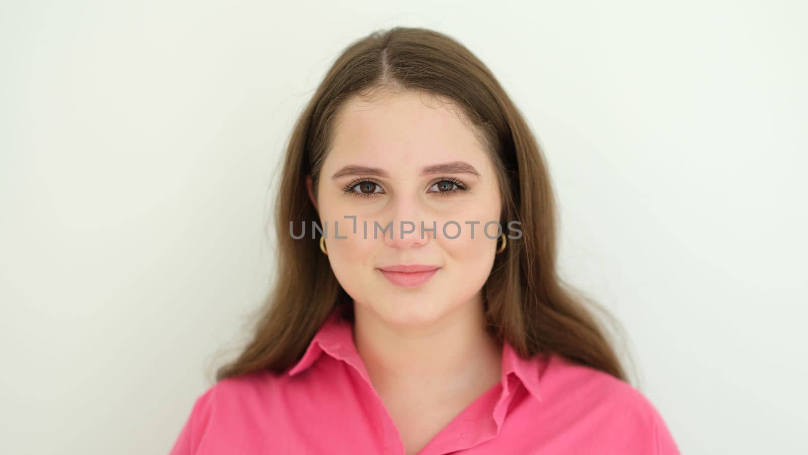 Portrait of young woman in pink shirt on white background. Healthy lifestyle concept