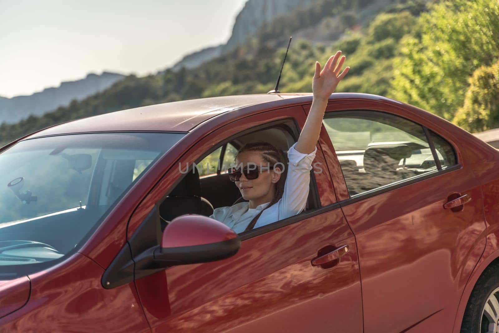 Woman driving a car. A lady in sunglasses takes the wheel of her new car. Rides along the road against the backdrop of mountains and the sea. by Matiunina