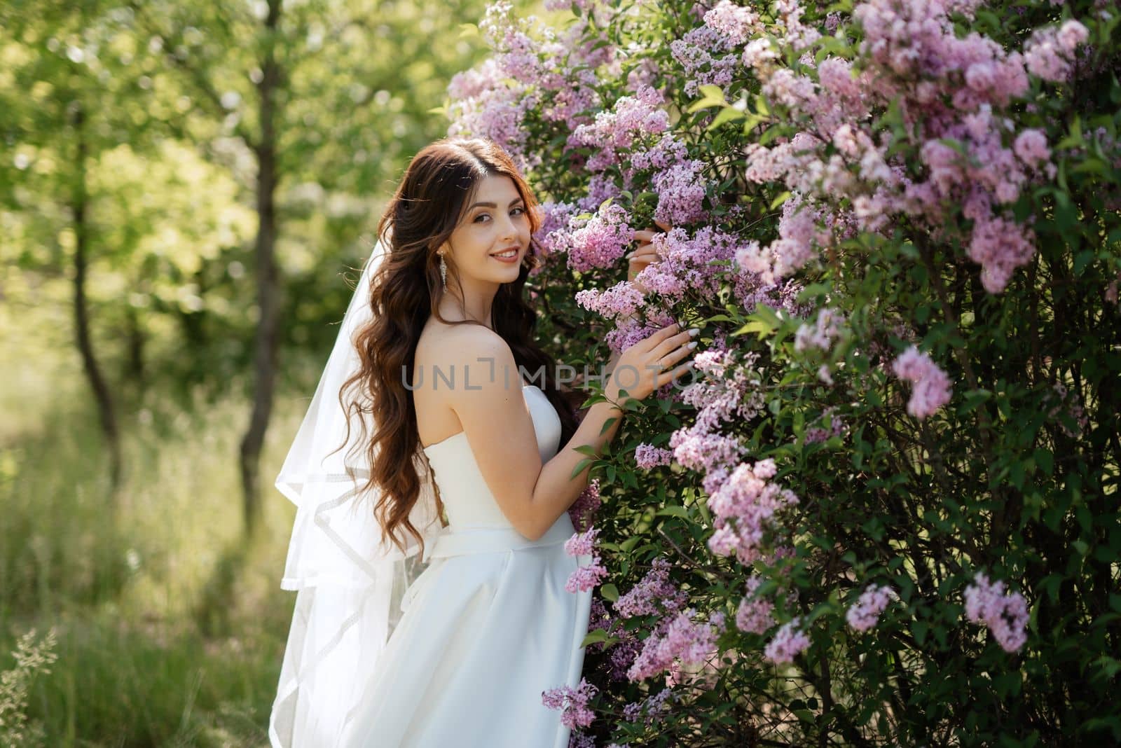 young girl bride in a white dress in a spring forest in lilac bushes by Andreua