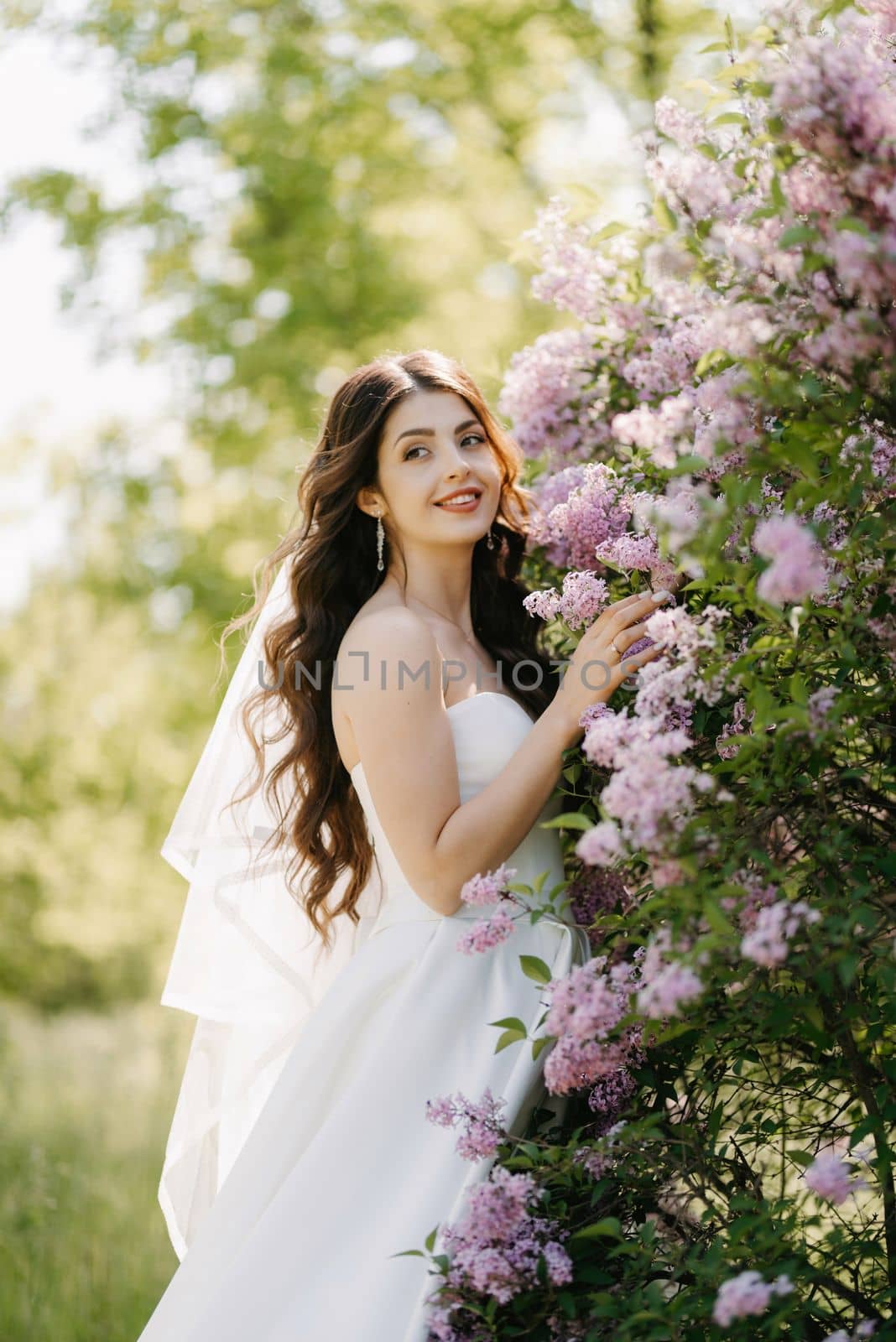young girl bride in a white dress in a spring forest in lilac bushes by Andreua
