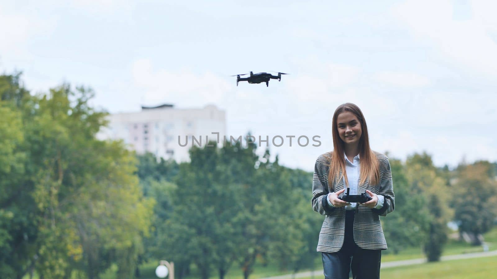 A cute girl controls a drone in the park