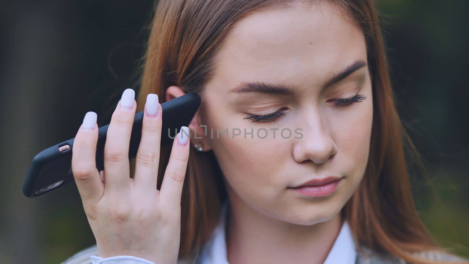 A young beautiful girl listens to an audio message on her phone