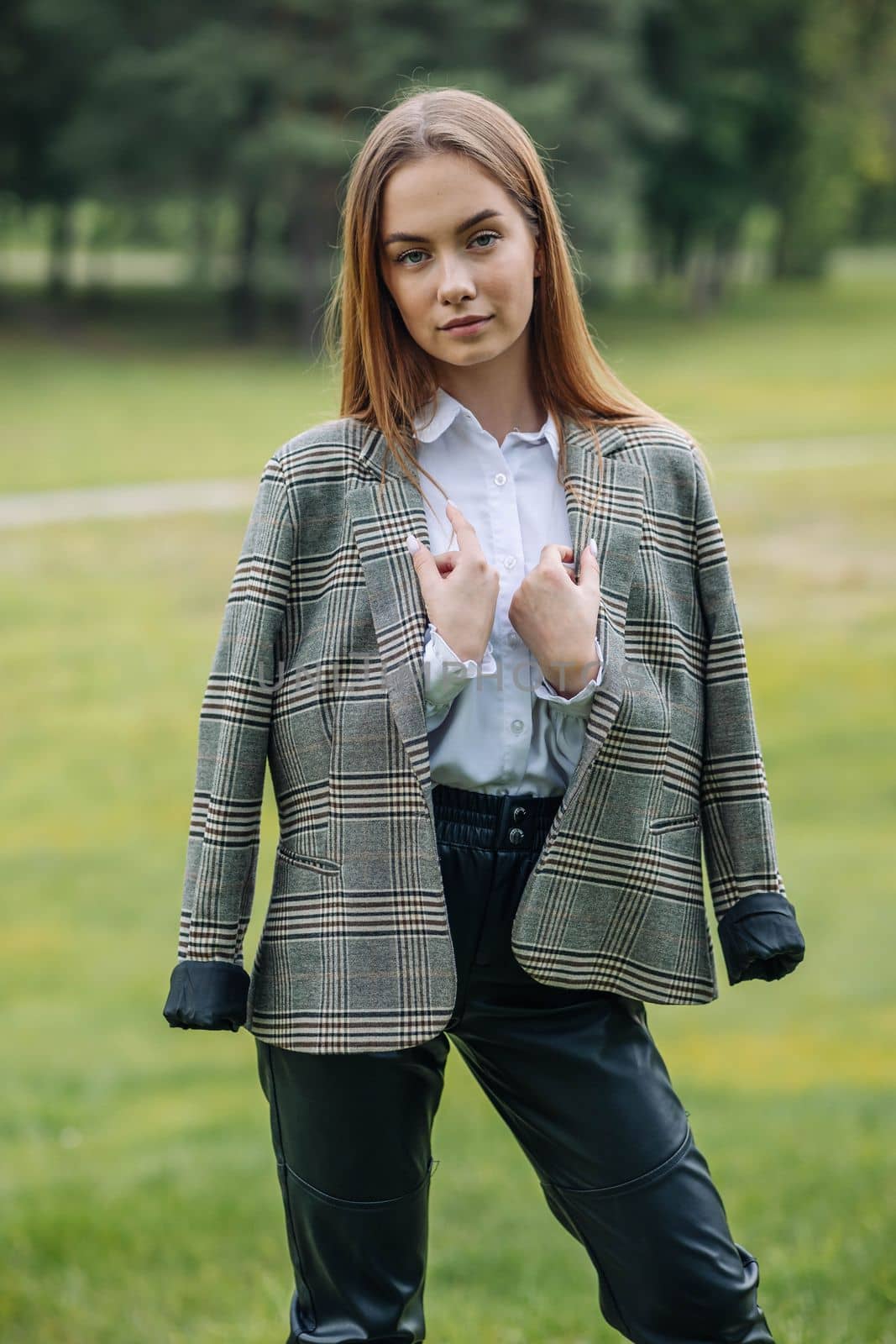 A young girl in a jacket poses in a park in the summer