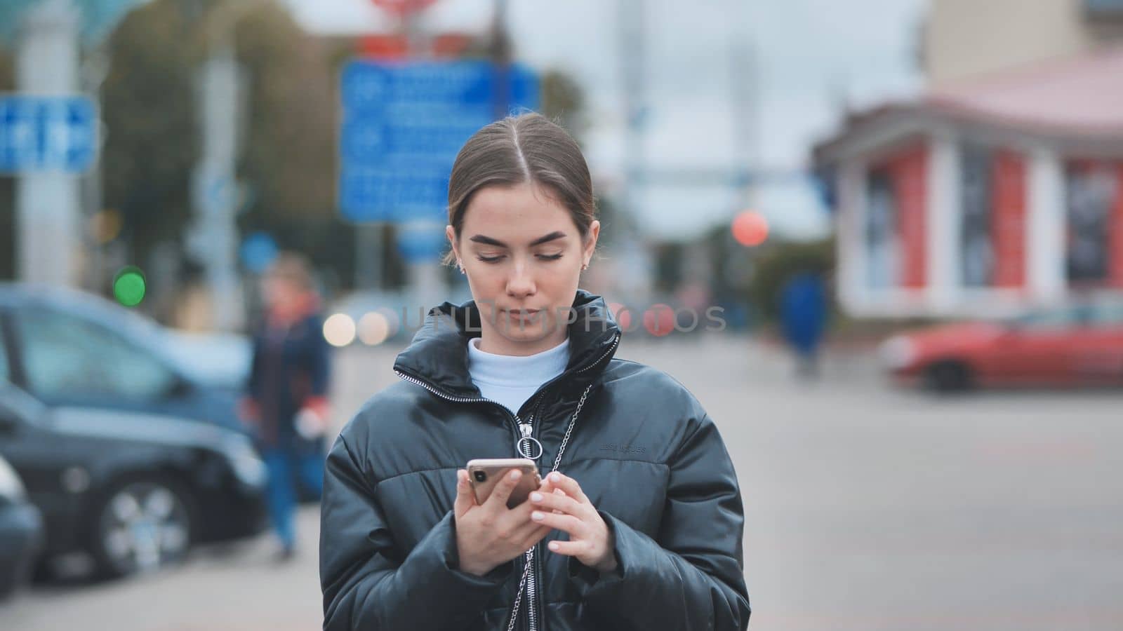 A girl walks through town and looks through her phone