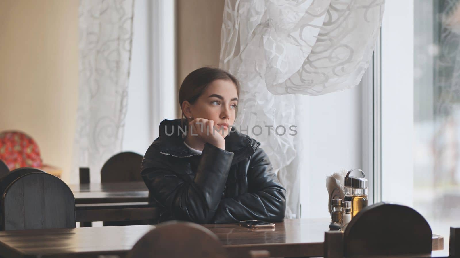 A lonely young girl sits in a cafe