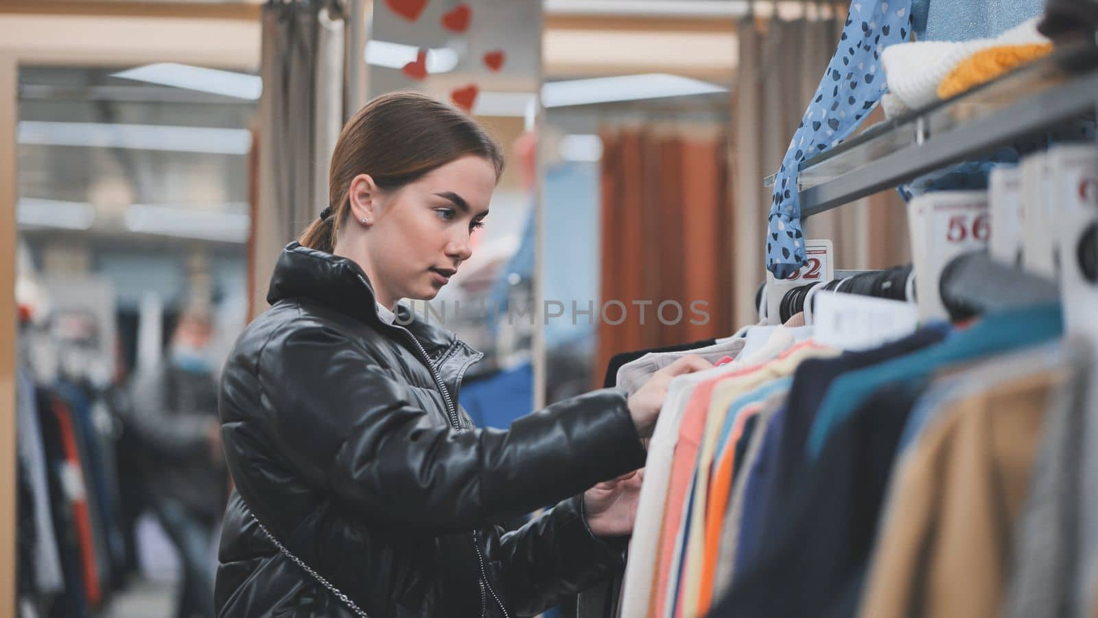 A young girl choosing and looking at clothes in the store