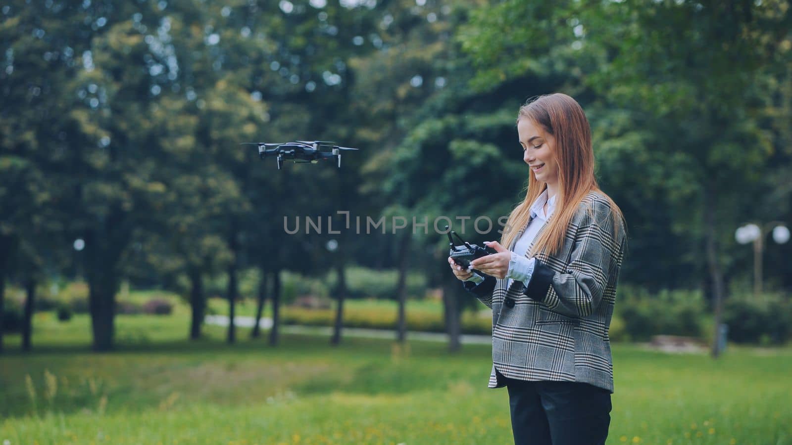 A cute girl controls a drone in the park