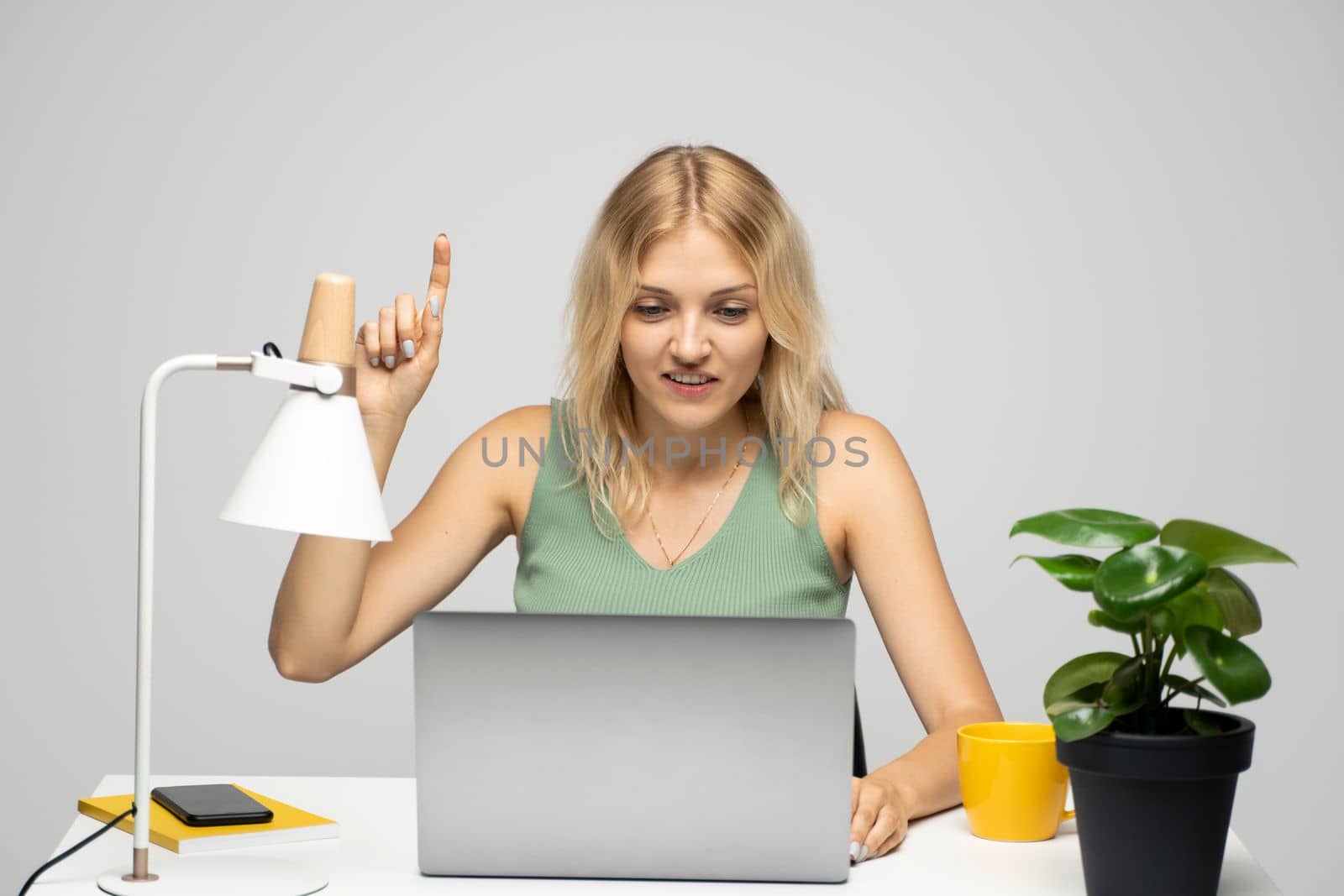 Happy woman pointing finger up while having an idea while working with a laptop a the table. Business plan, startup concept