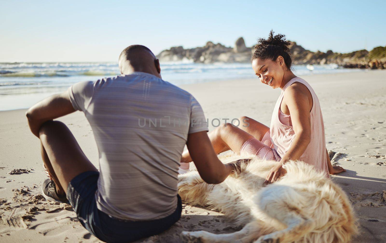 Fitness couple relax with dog at beach, sand and ocean after summer workout, free time and fun in sunshine together. Happy man, woman and people, labrador animal pets and freedom at calm sea outdoors.
