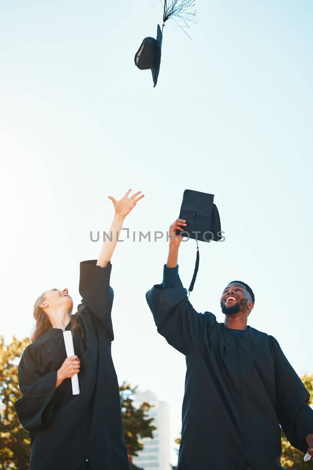 University, graduation and students with graduation cap in air for celebration, happiness and joy. College, education and man and woman throw hats after achievement of degree, diploma and certificate.