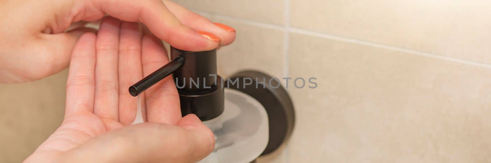 Washing and disinfecting hands, a woman uses liquid soap to wash her hands, in the bathroom, close-up. Place for text or copy space by SERSOL