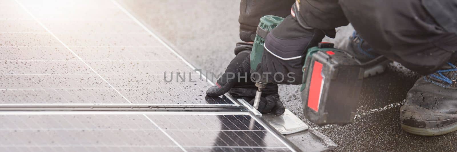 Renewable energy. Green energy concept. The process of installing solar panels. The master tightens the mounting of the solar panel module. by SERSOL